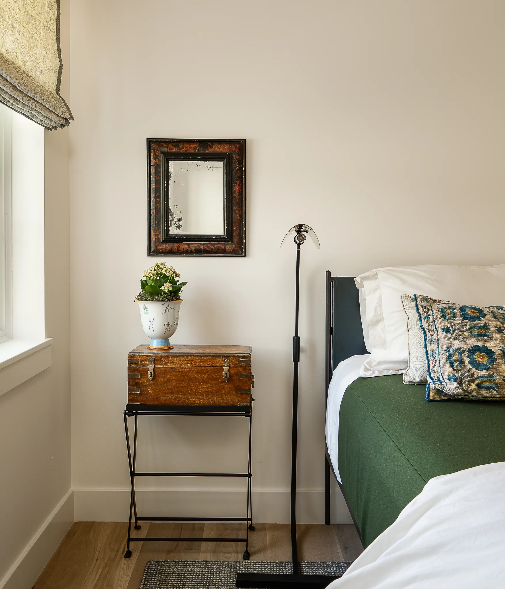 Bedroom nightstand with a vintage trunk beside a twin bed with green linens — interior design photography Driggs Idaho, WTG Architects